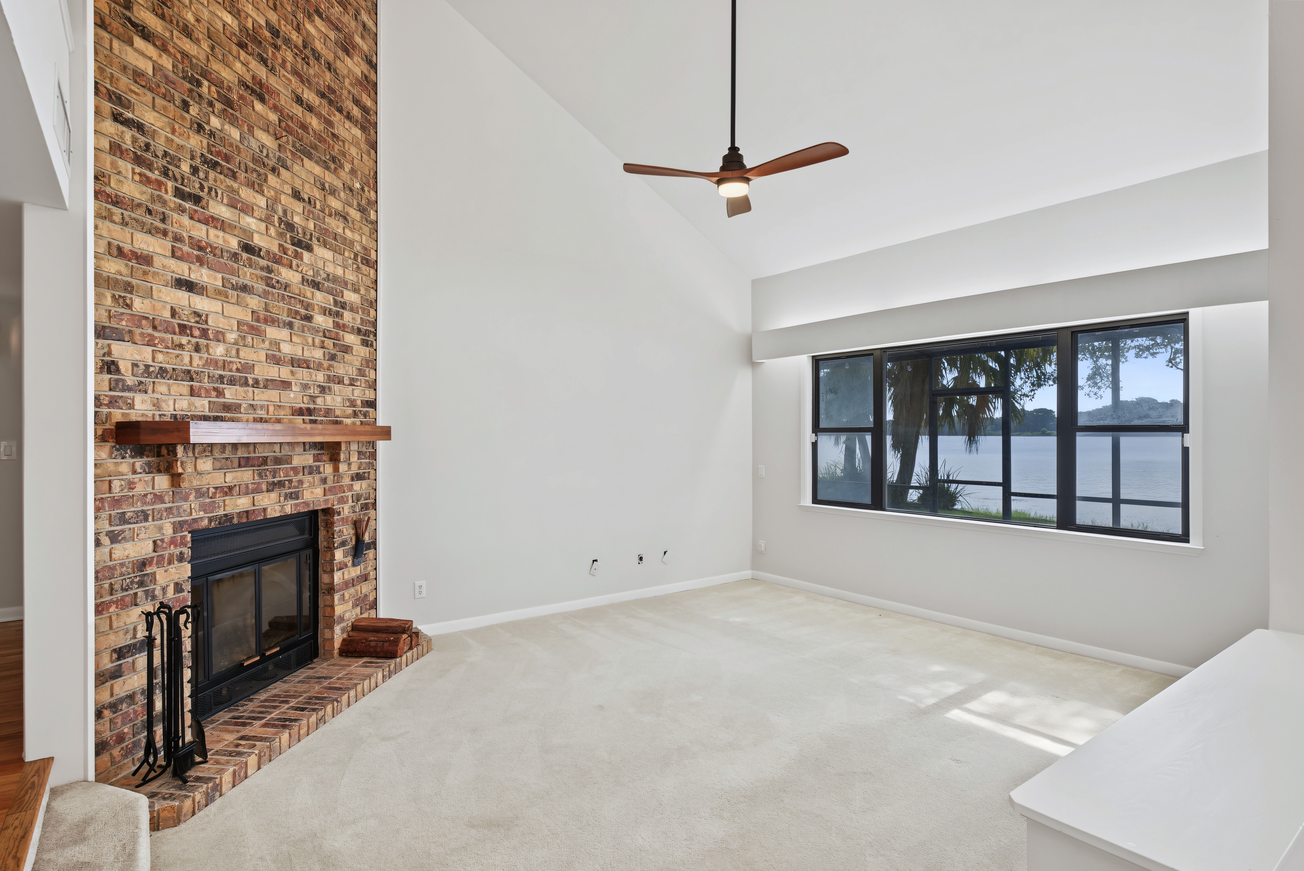 Original empty living room with a brick fireplace and large windows