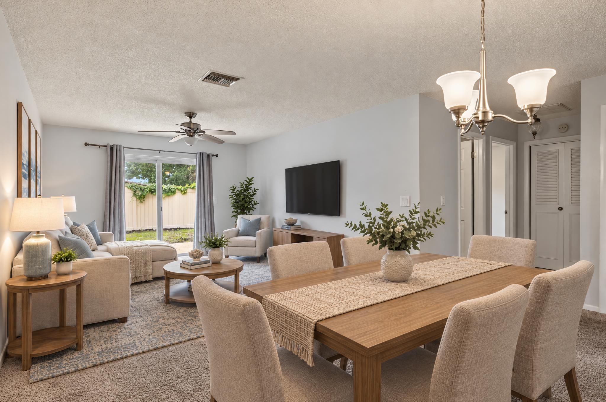 The same virtually staged living and dining room from the opposite angle, showing the coordinated sofa, dining table and TV console