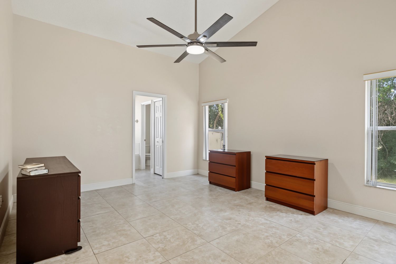 Original: the same primary bedroom, mostly empty with three mismatched dressers